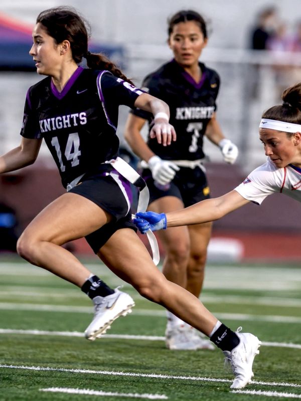Female flag football player evades a tackle in a game.
