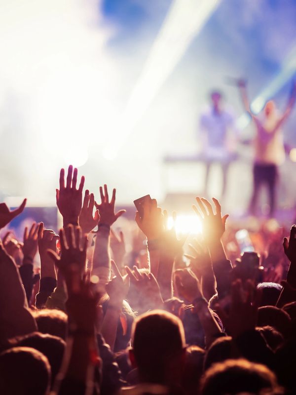 Raised hands at a lively concert with stage lights.