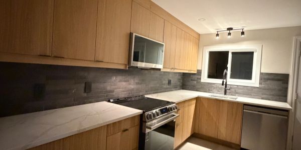 Modern kitchen with wooden cabinets and marble countertops.