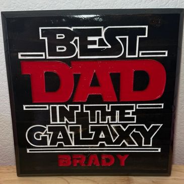 Decorative sign saying 'Best Dad in the Galaxy Brady' in bold letters.
