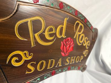 Wooden sign for Red Rose Soda Shop with decorative roses.