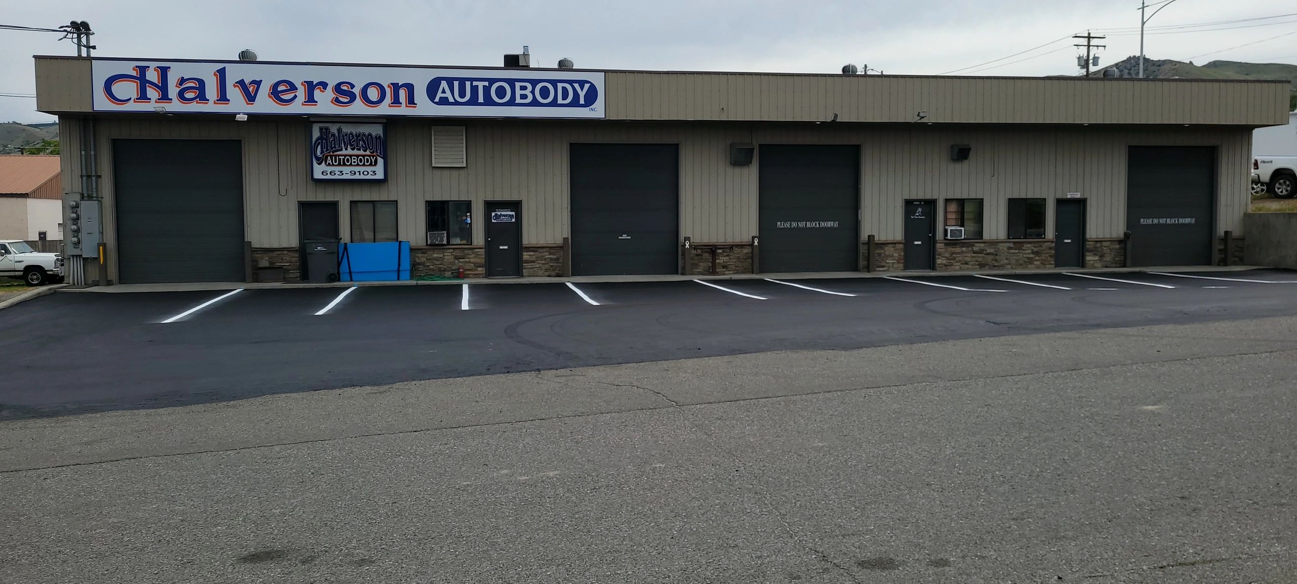 Exterior view of Halverson Autobody with parking spaces and closed garage doors.
