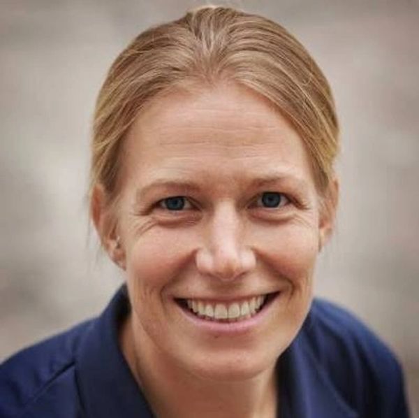 Close-up of a smiling woman with blonde hair and blue eyes.
