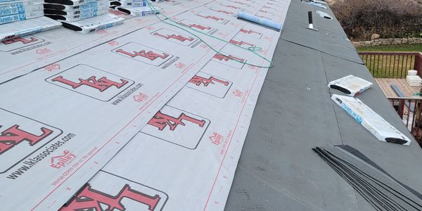 Roof underlayment being installed on a sloped roof before shingles.