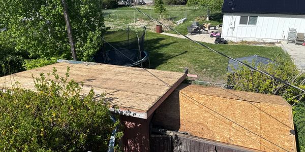 Two flat wooden roofs under construction in a grassy backyard.