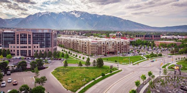 Urban buildings with mountain backdrop under a cloudy sky.