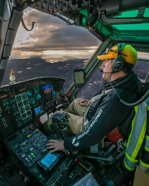 Pilot flying a helicopter at sunset.
