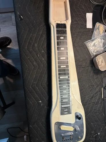 A disassembled lap steel guitar body on a black padded surface.