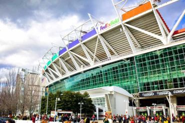Exterior view of a stadium with people gathered outside.