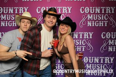 Three young adults in cowboy hats enjoying Country Music Night with drinks.