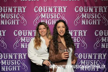 Two women smiling with drinks at a Country Music Night event.