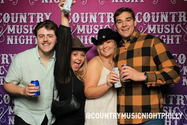 Four friends enjoying Country Music Night with drinks and cowboy hats.