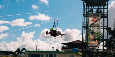 A person rides in Superman position down a tall zipline