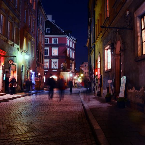 Cobblestone street with blurred people at night in a historic town.
