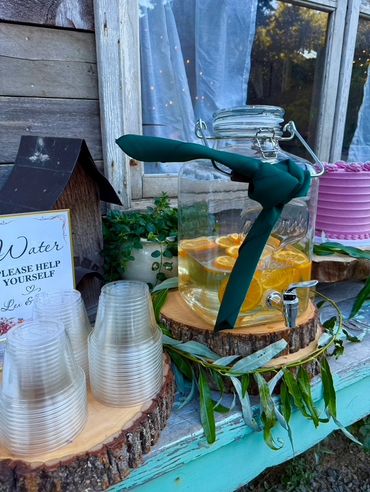 Outdoor beverage station with water and citrus drink.
