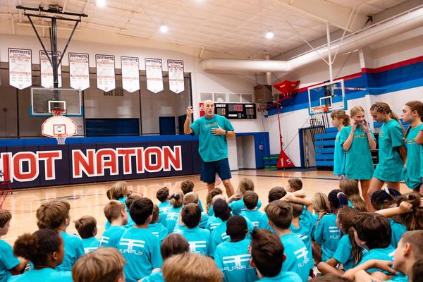 Kids listening to a coach teach them about basketball