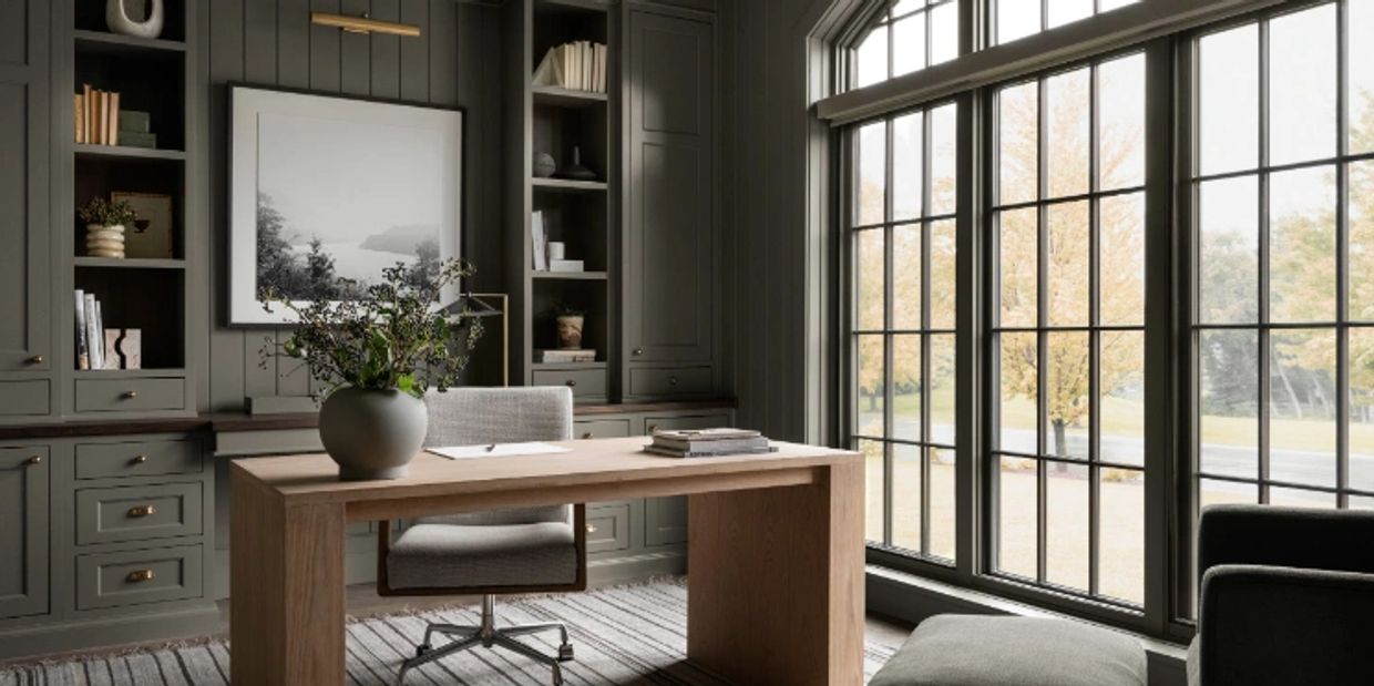 Home office with big windows, floor to ceiling cabinets and shelves, and workstation with a view.