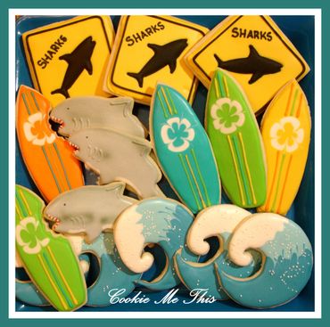 Colorful shark and surfboard themed decorated cookies.