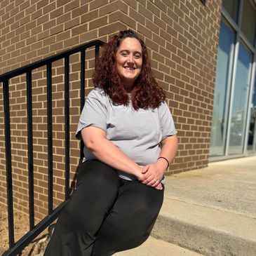Woman sitting outside on stairs smiling.