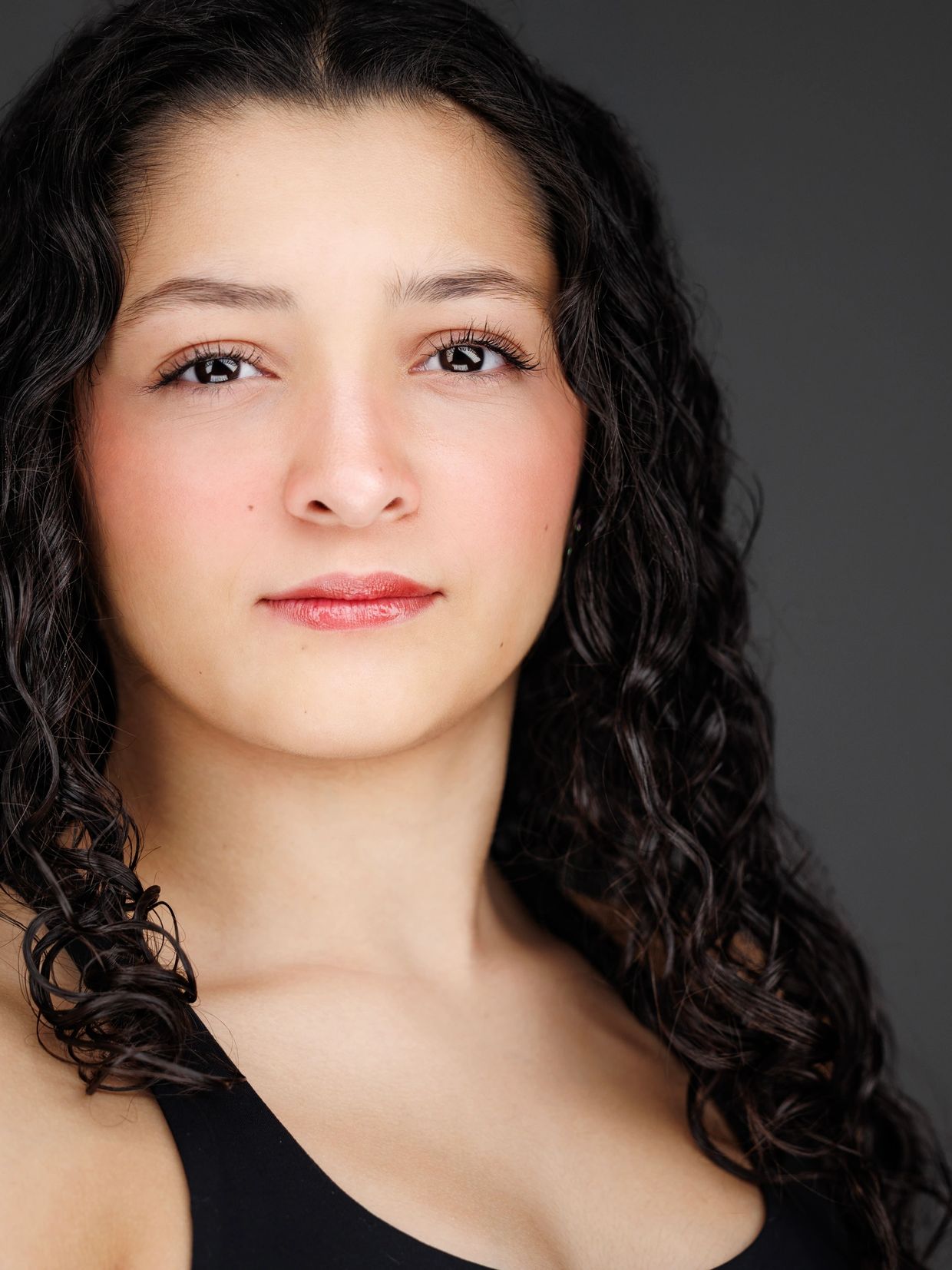 Close-up portrait of a woman with curly hair and a calm expression.