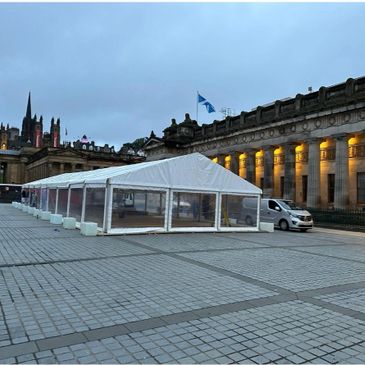 Large white event tent set up in a historic city square at dusk.