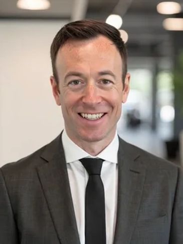 A man in a suit smiling indoors.