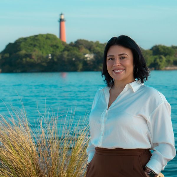 Studio owner, Adrianna Folkes on the shore of the Jupiter Inlet. Lighthouse in background.