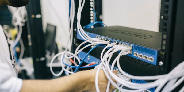 Technician working on network switches with connected cables.