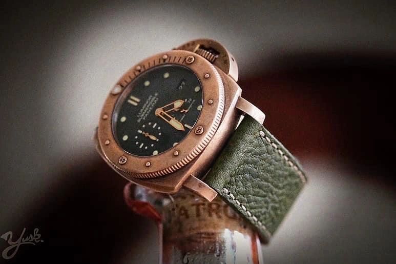 Close-up of a vintage bronze wristwatch with a green leather strap.