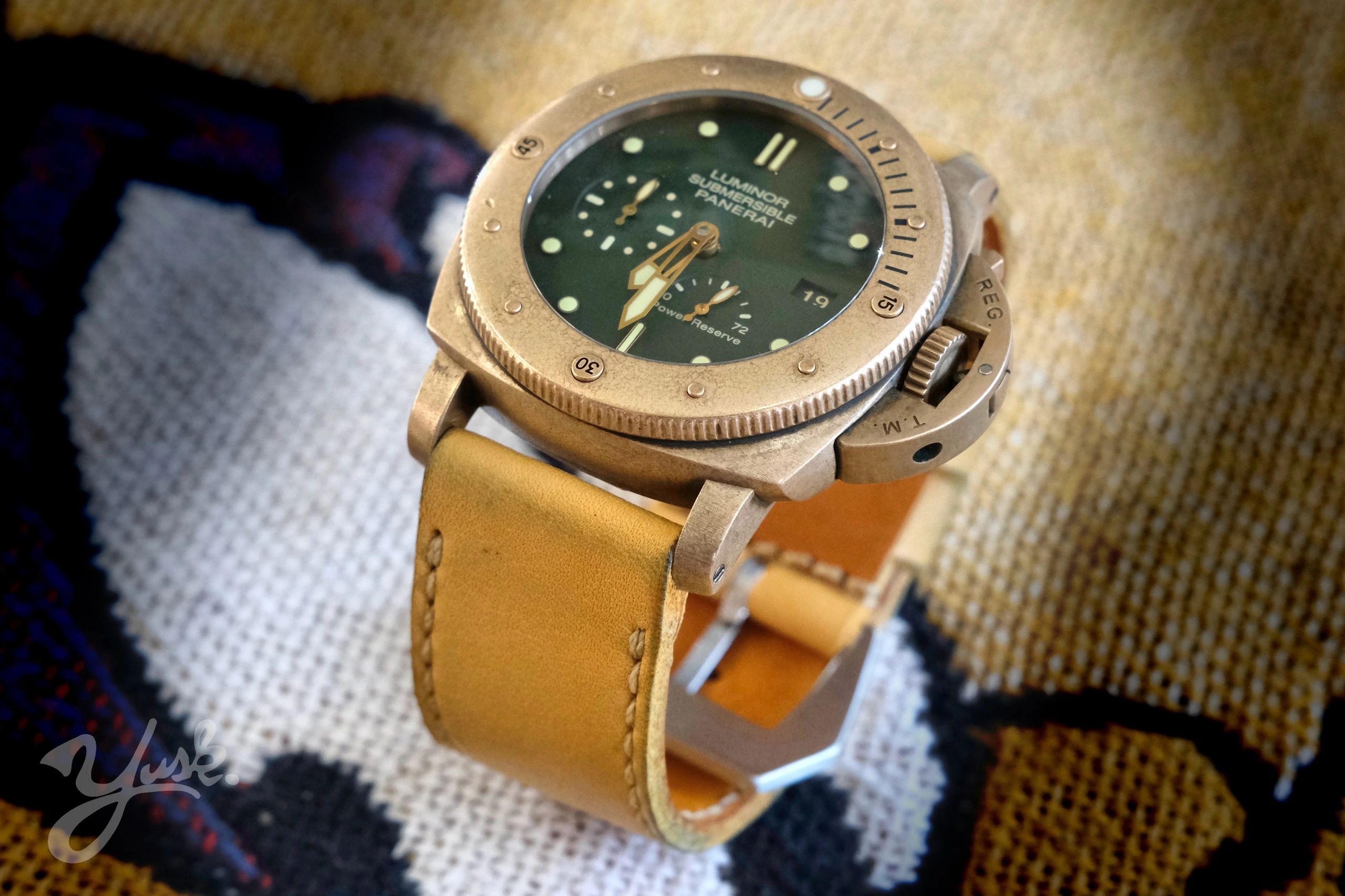 Close-up of a vintage Panerai Luminor Submersible watch with a tan leather strap.