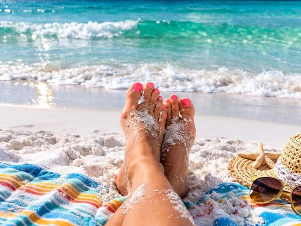 Iconic photo of a woman's toes in the sand near the shoreline.