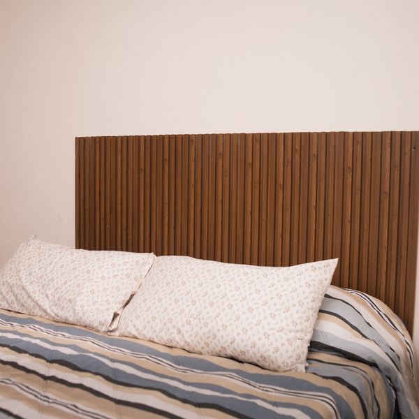 Cozy bed with striped bedding and floral pillows against a wooden headboard.