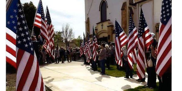People holding American flags outside a building.