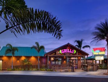 Tropical-themed Grills Tiki Bar restaurant illuminated at dusk.