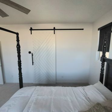 Modern bedroom with a white sliding barn door and a four-poster bed.