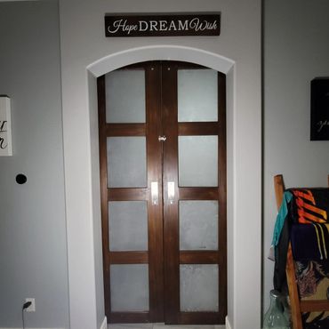 Wooden double doors with frosted glass panels under a "Hope Dream Wish" sign.