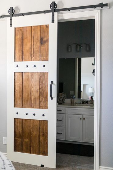 Rustic sliding barn door partially open to a modern bathroom.