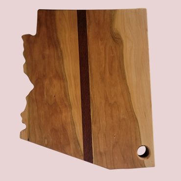 Wooden cutting board shaped like Arizona with a dark stripe and a hole.