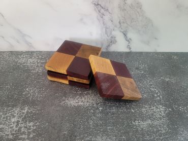 Two wooden checkered coasters on a textured surface.