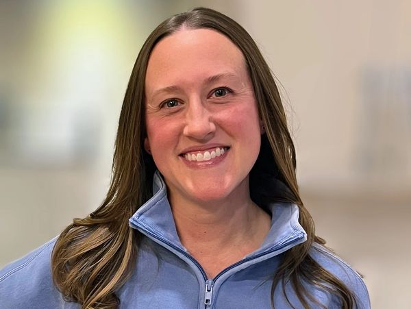 Smiling woman with long hair wearing a blue jacket.