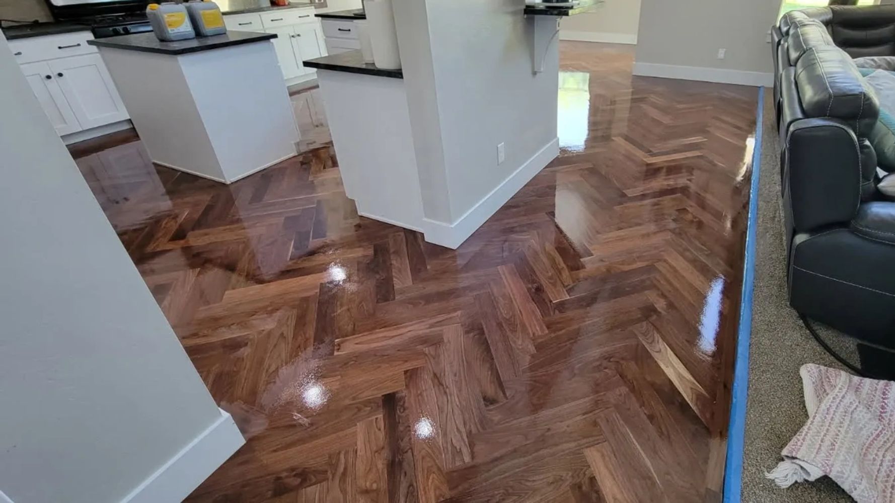 Glossy herringbone wooden floor in a modern kitchen and living area.