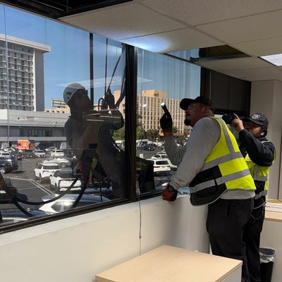 Workers installing or repairing a window from inside a building.