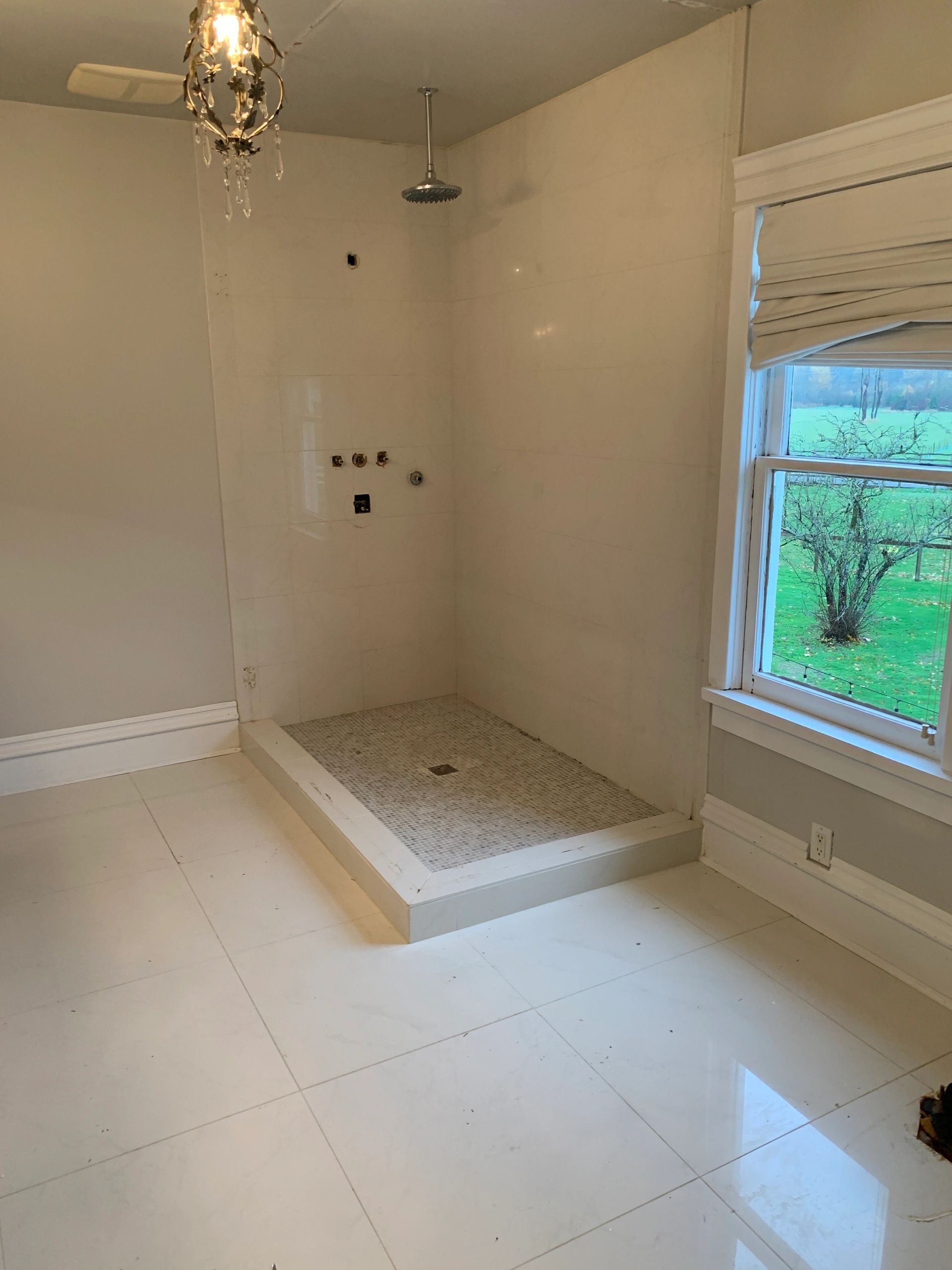 Unfinished shower with window view and chandelier.