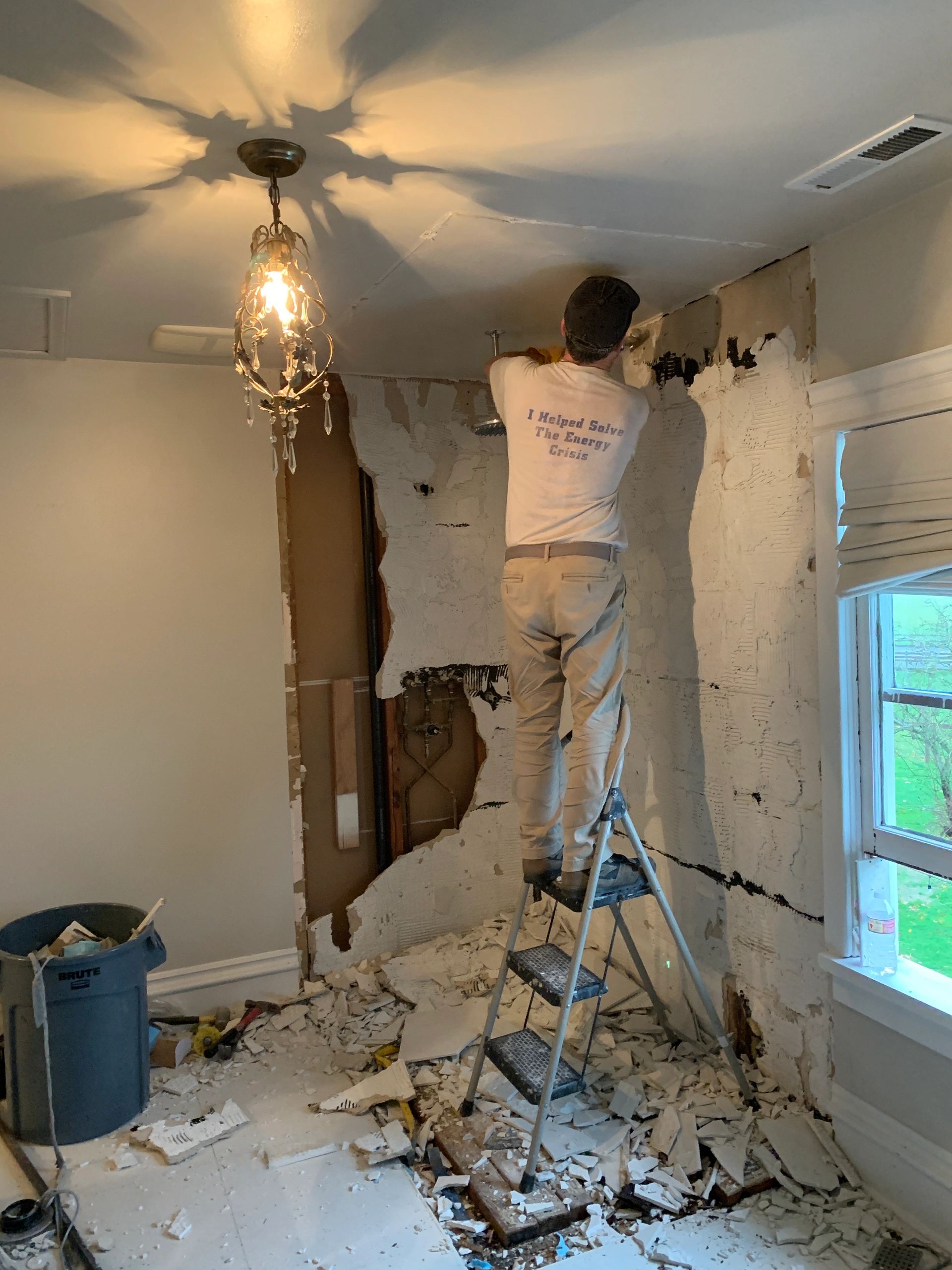 Person demolishing a wall in a room.