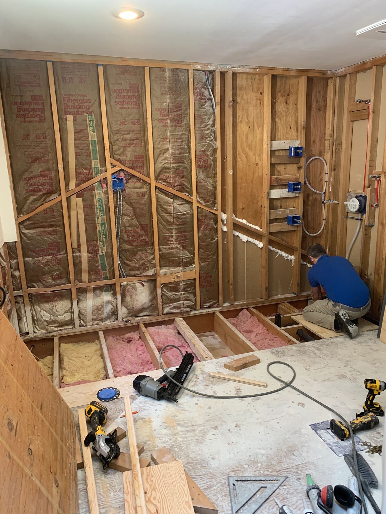 Man working on home renovation with exposed walls and floor.