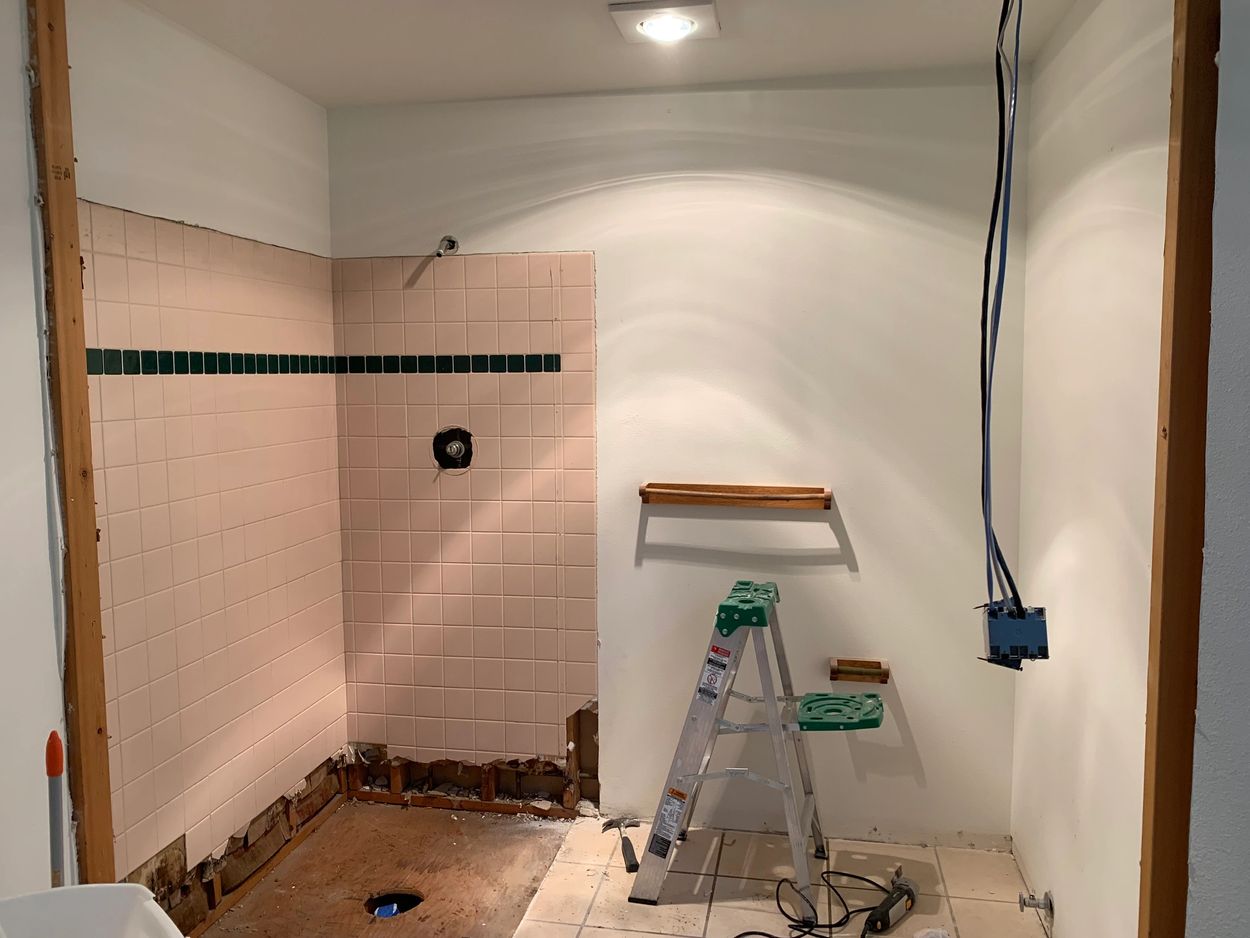 Bathroom under renovation with removed fixtures and exposed pipes.