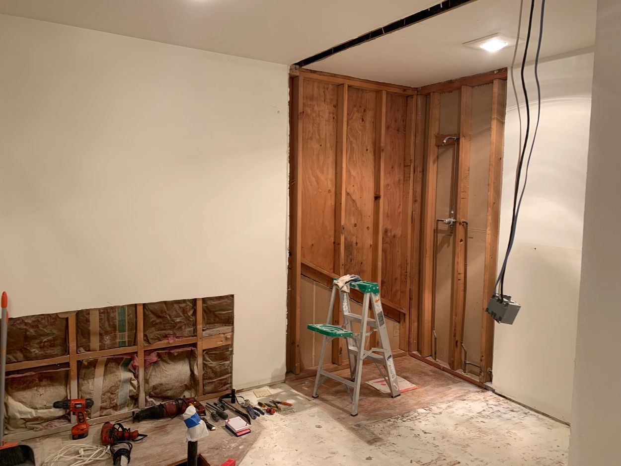 Room renovation in progress with exposed studs and tools.