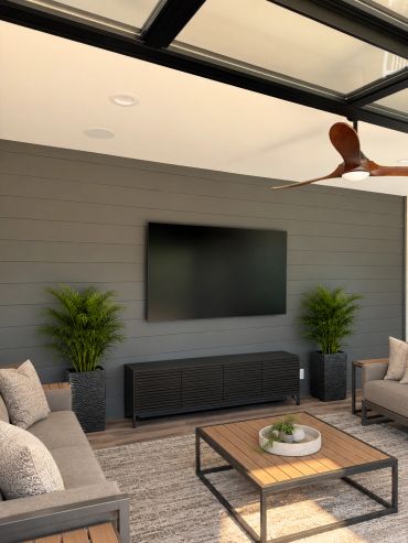 Custom outdoor entertainment space featuring a professionally mounted TV, in-ceiling speakers, and a