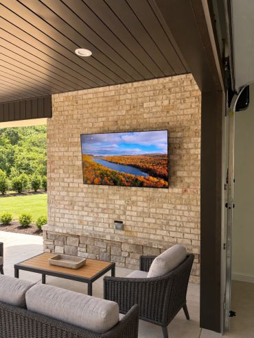 Custom covered-patio entertainment area featuring a professionally mounted outdoor TV, in-ceiling sp