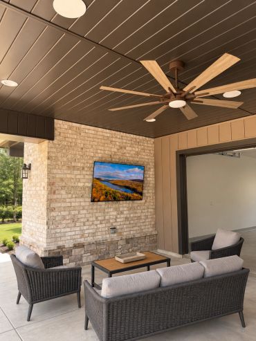 Custom covered-patio entertainment area featuring a professionally mounted outdoor TV, in-ceiling sp